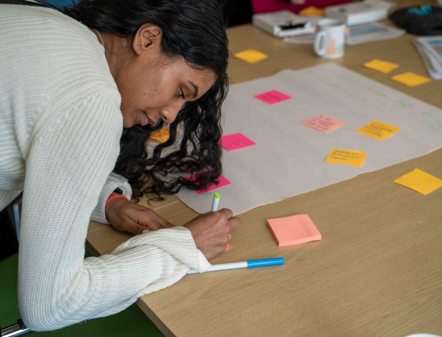 Young person writing on a post-it note during a workshop