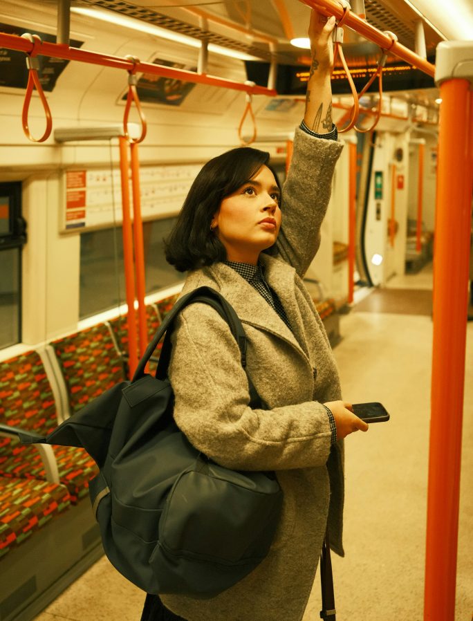 A woman commuting standing on the london tube holding on to the handrail
