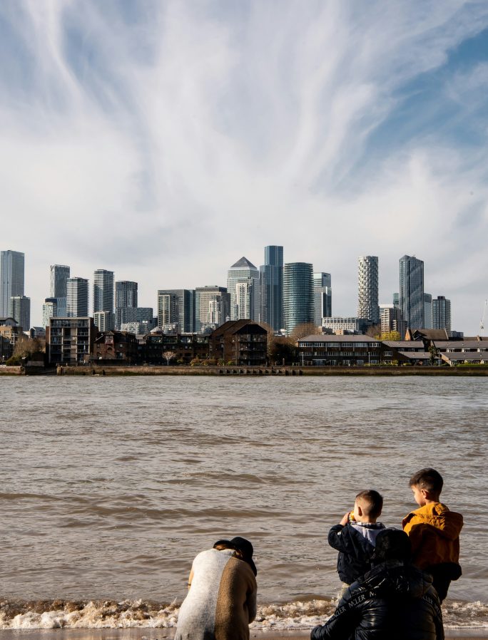 A family look across the river Thames towards Canary Wharf